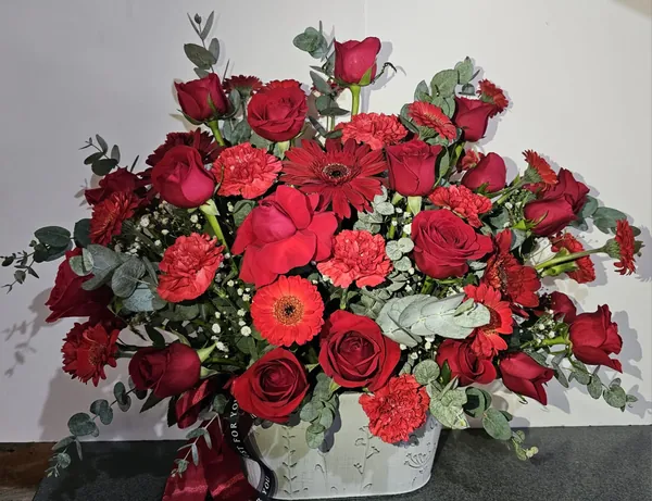 Arreglo abundante de rosas y gerberas rojas en base blanca