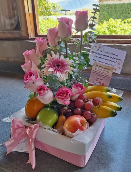 Caja de rosas rosadas con frutas frescas variadas