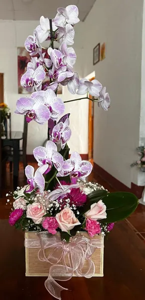 Orquídeas moradas con rosas en caja de madera clara