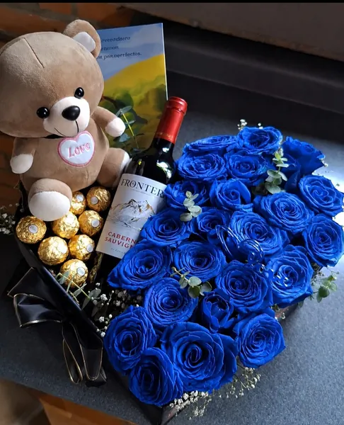 Rosas azules en forma de corazón con osito, chocolates y vino