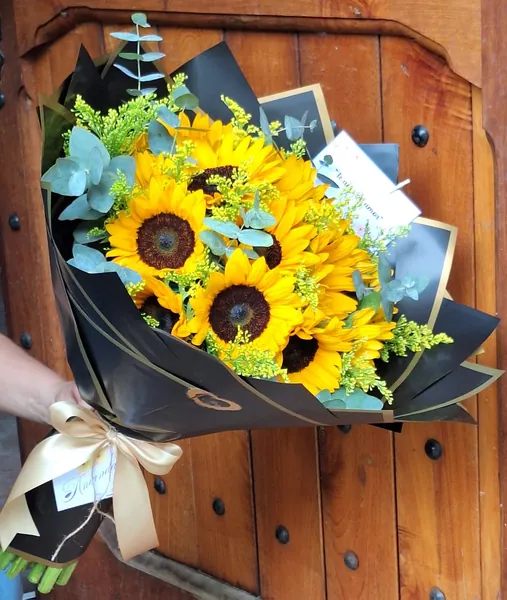Ramo de girasoles y solidago con envoltura negra y dorada