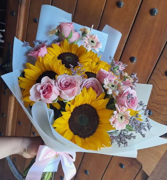 Ramo de girasoles y rosas rosadas en papel blanco