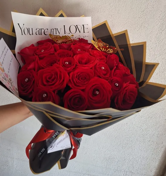 Ramo de rosas rojas con envoltura negra y dorada y mariposas doradas