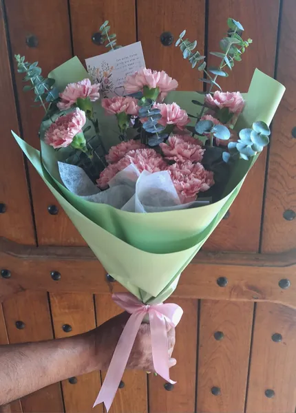 Ramo de claveles rosados con eucalipto en papel verde